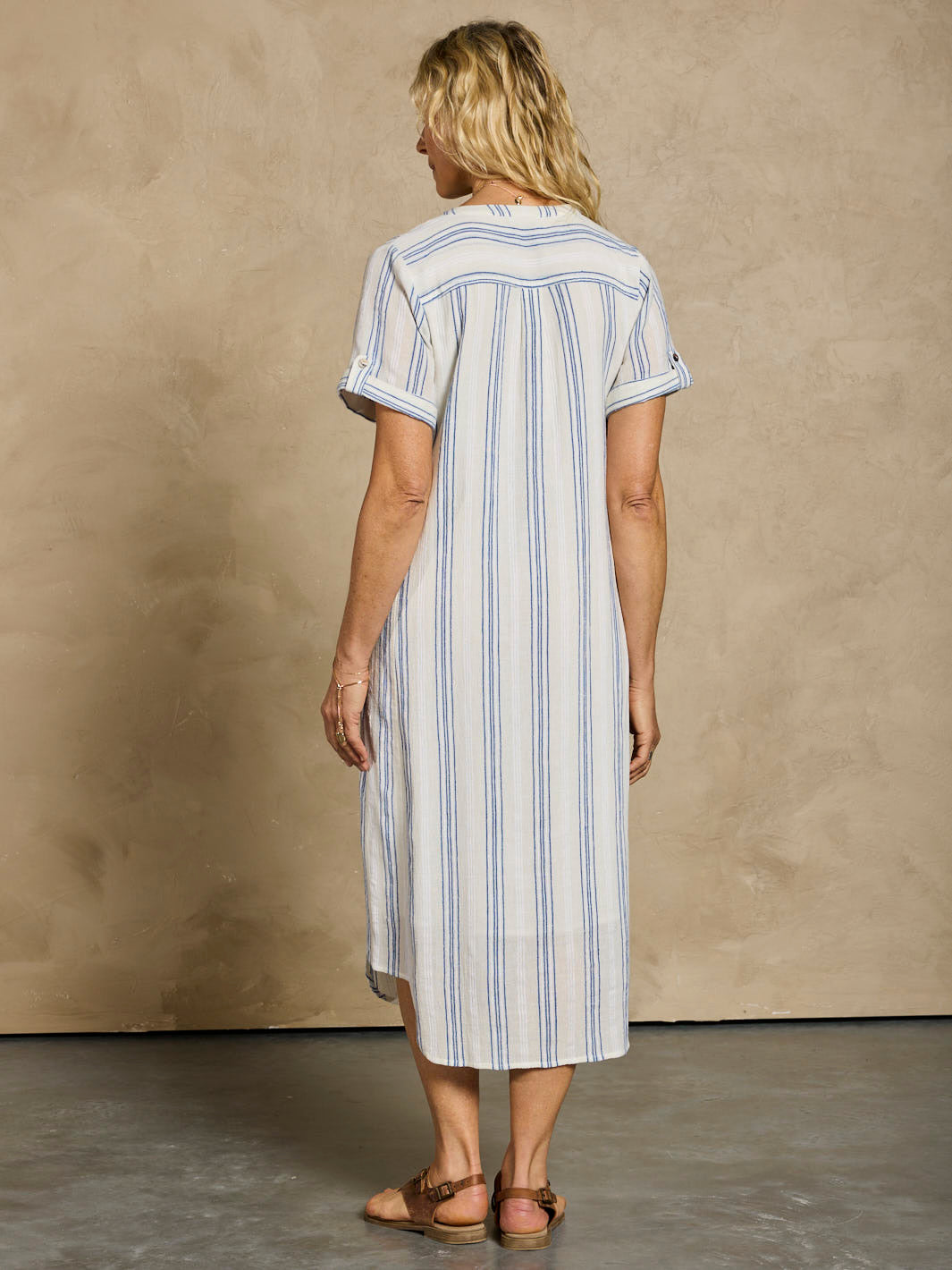 Woman wearing a striped dress against a beige wall