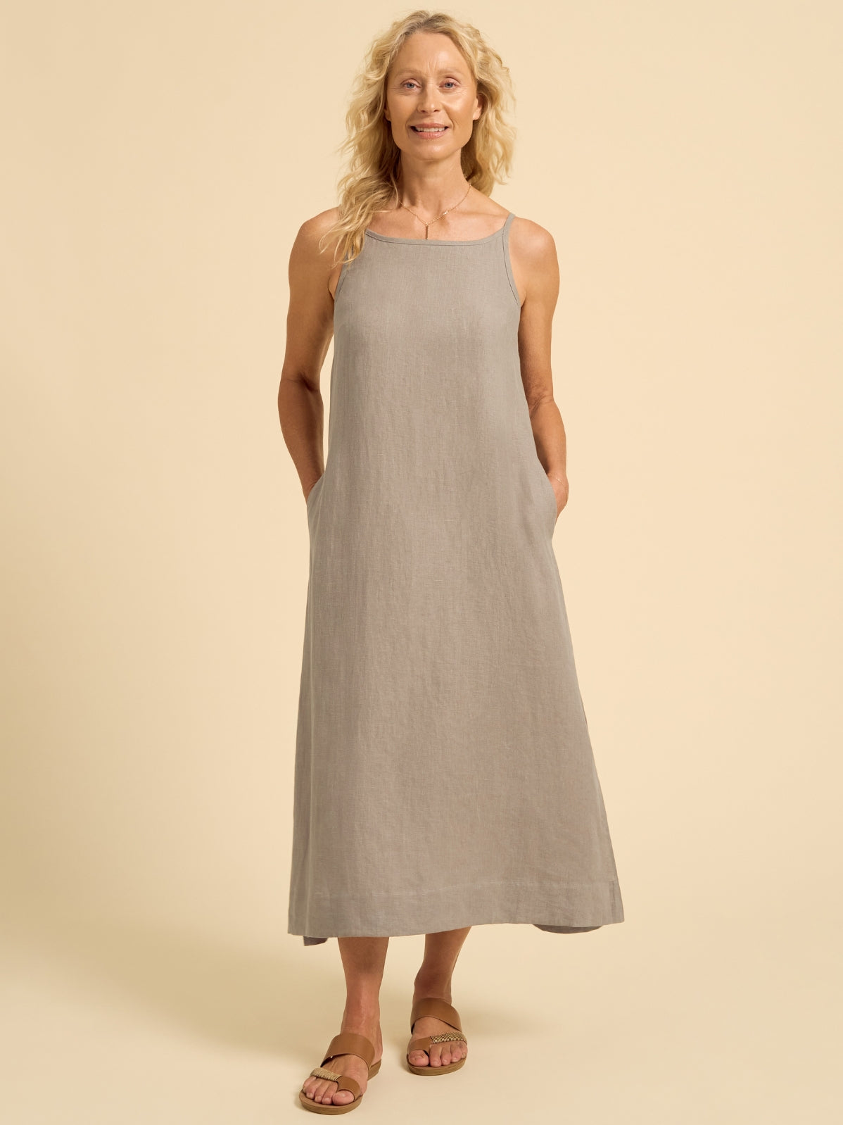 Woman wearing a gray sleeveless dress on a beige background