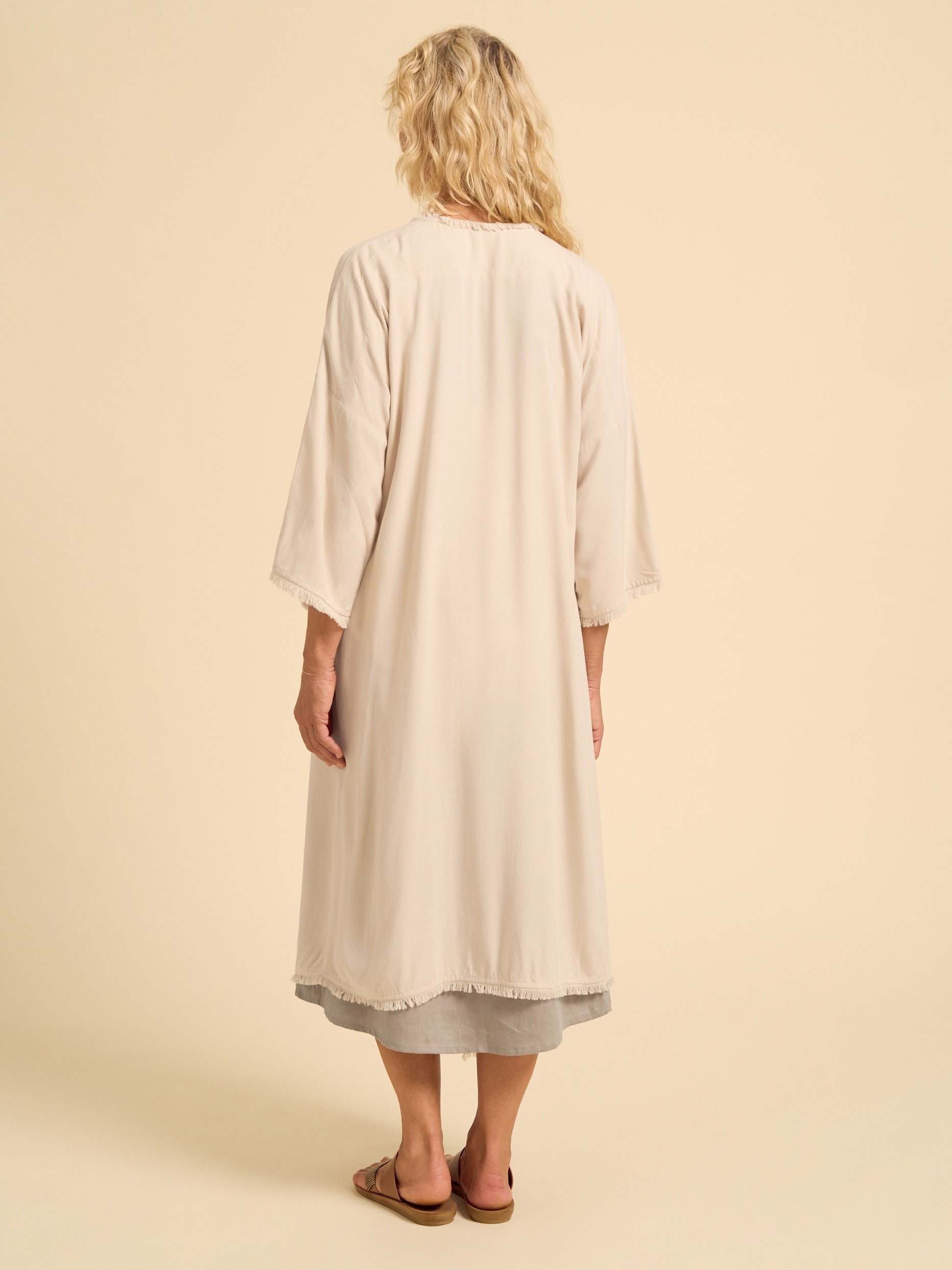 Woman wearing a beige dress against a beige background